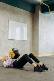 女人抱球躺在瑜伽垫上运动图片