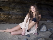 坐在沙滩岩洞里的性感美女图片