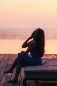 日暮黄昏坐在海边长椅上的美女剪影图片