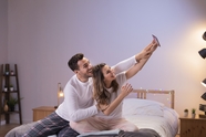 卧室内手持手机自拍的情侣图片