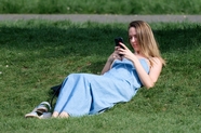 躺在绿色草地上看手机的美女图片